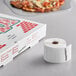 A roll of white paper TamperSafe labels next to a white pizza box.