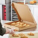A person putting croissants in a Kraft pizza box.
