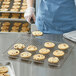 A person in blue gloves placing a cookie on a Fat Daddio's stainless steel cooling rack.