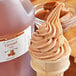 A scoop of caramel ice cream with a bottle of LorAnn Caramel Super Strength Flavor on a table.