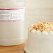 A white cake with coconut flakes next to a gallon of LorAnn Oils Coconut Bakery Emulsion.