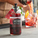 A person using a Rokz Wild Hibiscus Cocktail Infusion kit to pour a red liquid into a glass.