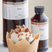 A cupcake with whipped cream and pecans next to a bottle of LorAnn Oils Pecan Super Strength Flavor.