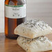 A bottle of LorAnn Oils Rosemary Super Strength Flavor next to two rolls of bread.