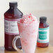 A glass cup of pink liquid with candy canes next to a bottle of LorAnn Oils Peppermint Bakery Emulsion.