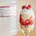 A glass of raspberry trifle next to a bottle of LorAnn Oils Raspberry Bakery Emulsion.