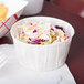 A white paper Solo portion cup filled with coleslaw and fries on a counter.