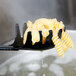 A black plastic pasta fork with pasta on it.