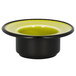 A black bowl with a yellow rim on a green RAK Porcelain saucer.