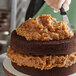 A person spreading Rich's German Chocolate cake icing on a cake.