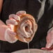 A person holding a glazed doughnut with Rich's Donut Glaze.