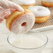 A hand dipping a Rich's Vanilla Heat 'n Ice glazed donut into a bowl of milk.