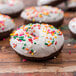 A group of gluten free chocolate donuts with Rich's Vanilla Heat 'n Ice white frosting and sprinkles.