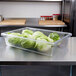 A Carlisle clear plastic food storage box on a counter filled with lettuce.