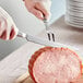 A person using a Choice stainless steel carving knife to cut meat.