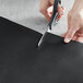 A person cutting a piece of black material with a pair of scissors.