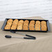 A black Siciliano rectangular melamine tray with cookies and tongs.