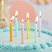 A white birthday cake with six Creative Converting assorted pastel spiral candles on it.