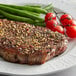 A piece of meat with Regal Canadian Steak Seasoning on it served with green beans and tomatoes.