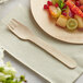 A TreeVive by EcoChoice wooden fork next to a plate of fruit.