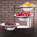 An American Metalcraft three-tiered display stand with fruit on it.