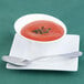 A white Arcoroc Ludico deep bowl filled with tomato soup with a silver spoon.