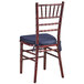 A Lancaster Table & Seating mahogany wood Chiavari chair with navy blue cushion.