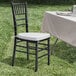 A Lancaster Table & Seating black wood Chiavari chair with a white cushion on a table