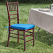 A Lancaster Table & Seating mahogany Chiavari chair with a blue cushion on it.