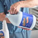 A person pouring Noble Chemical QuikSan sanitizer into a plastic jug.