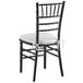 A Lancaster Table & Seating black wood Chiavari chair with ivory cushion.