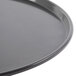 A close-up of a black Chicago Metallic BAKALON pizza pan with a round edge.