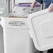 A large white storage bin labeled 'Baker's Lane' is being opened, revealing a scoop and granular contents inside.