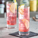 Two Pasabahce highball glasses filled with pink lemonade and ice, garnished with lemon slices.