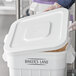 A white plastic bin with a partially open lid, labeled 'BAKER'S LANE,' containing a brown granular substance.
