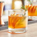 A Pasabahce double old fashioned glass of orange drink with a rosemary sprig.