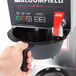 A person using the touchpad controls on a Bloomfield commercial coffee maker.