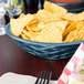 A blue polyethylene basket filled with chips on a table.