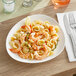 A plate of Acopa Nova stoneware with shrimp and pasta with a lemon slice.