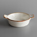 A white stoneware mini casserole dish with brown specks on the surface and handles.