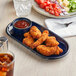 An Acopa Azora blue stoneware platter with fried chicken wings and red sauce.