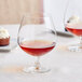 A table with a glass of red liquid in an Acopa Covella brandy snifter next to a cupcake.