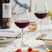A table set with Acopa Radiance wine glasses and a glass of red wine on a table.