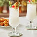 Two Acopa Select stemmed glasses filled with white drinks and pineapple garnish.