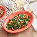 An Acopa Capri coral reef oval stoneware coupe platter with salad and corn on it on a table with a fork and a bowl of corn and beans.