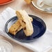 An Acopa Keystone Azora Blue stoneware coupe plate with two pieces of biscotti on it.