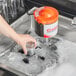 A hand using a 7 1/2" replacement glass washer brush to clean a glass in a sink.