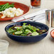 An Acopa Keystone Azora Blue stoneware coupe bowl filled with salad on a table.