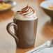 A close-up of a cup of hot chocolate with whipped cream in an Acopa Embers hickory brown matte stoneware mug.