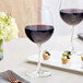 Two Acopa Covella Bordeaux wine glasses on a table with a glass of red wine and a meal.